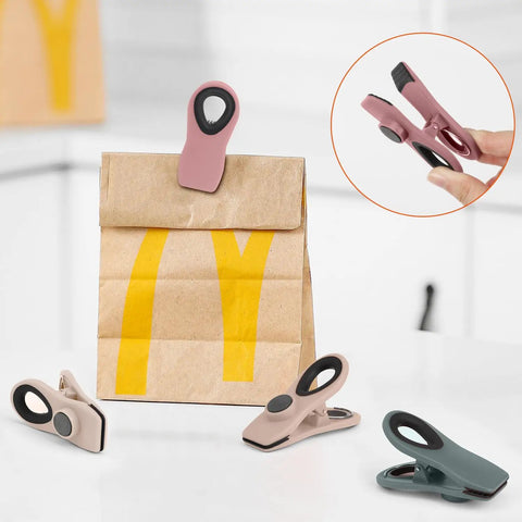 Game Changer Heavy Duty Magnetic Clips Keep Chips And Snacks Locked Down Crisp Through The Week Assorted Muted Tones on a brown bag.