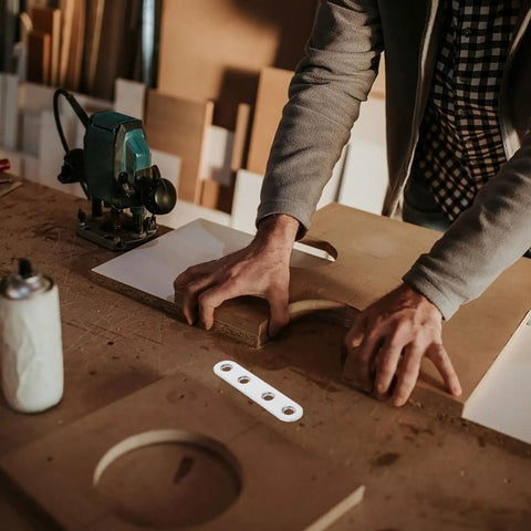Carpenter using heavy duty stainless steel shelf brackets set with four hole flat brackets and 120 screws in workshop.