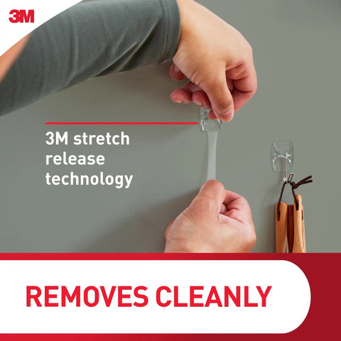 Person removing Clear Small Wire Toggle Hooks Set with 10 wall hooks and 12 adhesive strips, damage-free hanging with no holes.