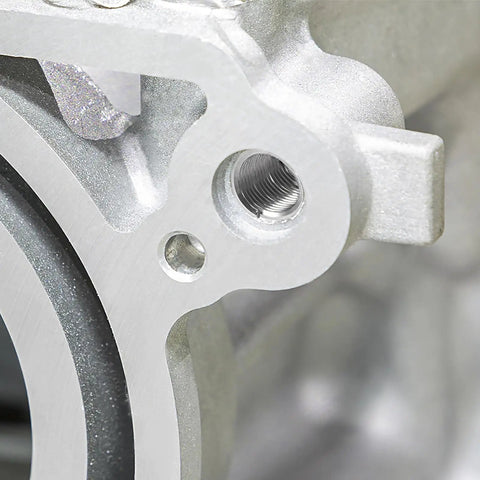 Close-up of a threaded hole in heavy machinery component showcasing Built Like A Tank 20 Piece Wire Thread Inserts In 1/4 20 UNC Helical Coil Format Crafted From Durable 304 Stainless Steel For Effortless Rust Proof Thread Fixes On Heavy Machinery.