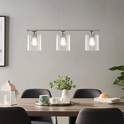 Three Light Kitchen Island Fixture With Clear Glass Cylinder Shades In Warm Brass Finish over dining table