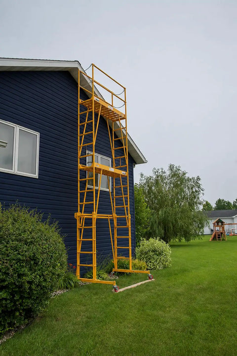Heavy Duty Adjustable Work Platform Featuring Locked Safety Rails against blue house, showcasing portability and height adjustment.
