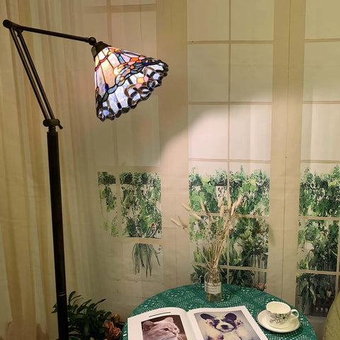 Blue Baroque Tiffany Style Stained Glass Swing Arm Floor Lamp, 75-Inch Tall with 10-Inch Shade next to a book and teacup