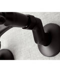 Close-up of a dark metal faucet arm, resembling the design of Two Handle Wall Mount Bathroom Faucet in Polished Nickel with Drip Free Ceramic Disc Cartridge, Adjustable Center from Three and a Half Inches to Eight and a Half Inches, 1.2 GPM Flow, Solid Brass Build, Sleek Dope Bath Upgrade.