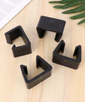 4 Pack Black Plastic Sofa Clips For Sectional Couches And Furniture Connectors on a wooden surface