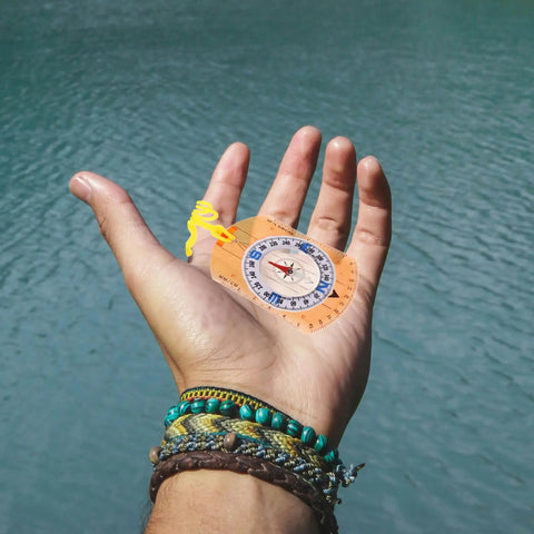 Hand holding Orienteering Compass For Hiking And Camping With Lanyard Multifunction Navigation Tool Lightweight Portable Trail Backpacking Compass In Orange