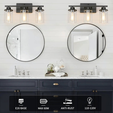 Slick Black 3 Light Vanity Light Fixtures Over Mirror With Clear Glass Shades mounted above double sinks in bathroom.