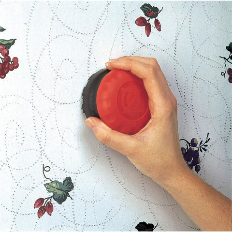 Hand using Wallpaper Remover Tool With Multi Directional Scoring Wheels For Easy Wallcovering Removal Perforates Thoroughly