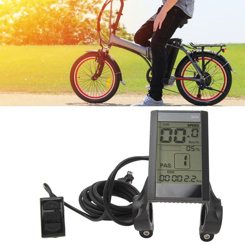 22.2mm LCD Cycling Computer For E Bikes Multifunctional Display Meter showcasing speedometer and battery voltage monitor. Bicycle in background
