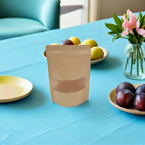 Resealable Kraft Paper Bags With Clear Window For Food Storage And Pantry Organization Pack Of 50 on a table with fruit and flowers.