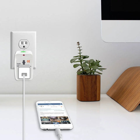 Portable Worldwide Universal Power Adapter All In One Travel Charger plugged in next to a smartphone on a desk