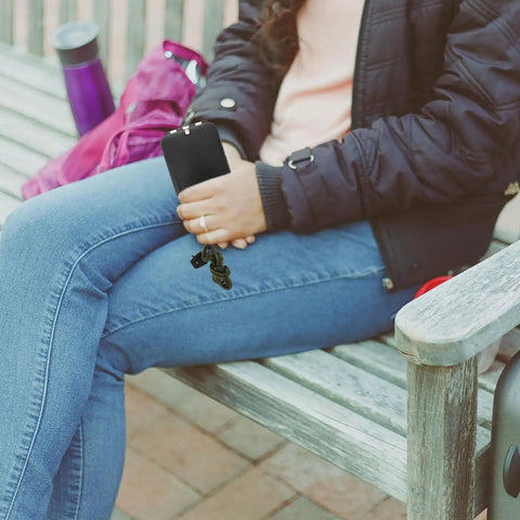 Person holding multifunction hiking compass with scale ruler and mirror for camping and outdoor orienteering on a bench.