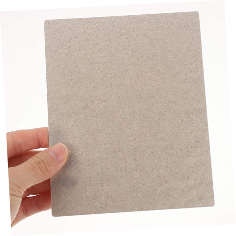 Hand holding high temperature mica sheet for microwave ovens, durable waveguide cover and heat resistant oven accessory.
