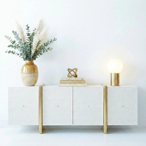 Kai LED Table Lamp With USB Port on modern white cabinet with globe shade, brass finish beside a vase and books