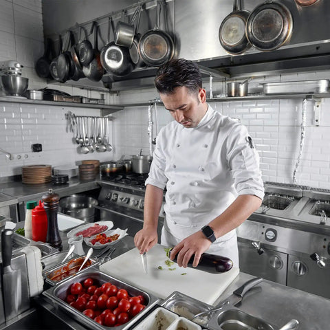 Chef slicing vegetables in a busy kitchen with Heavy Duty Stainless Steel Wall Mount Shelf 12X36 Inch NSF Certified Rust Proof Storage Rack.