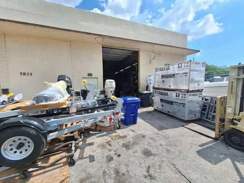 Outdoor facility with marine equipment including outboard motors and packing crates under a clear sky.