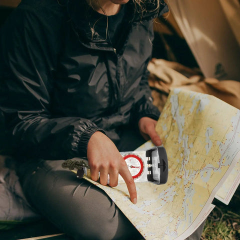 Person using Trail Ready Multi Function Orienteering Compass With Ruler And Luminous Mirror For Hiking And Camping on a map outdoors