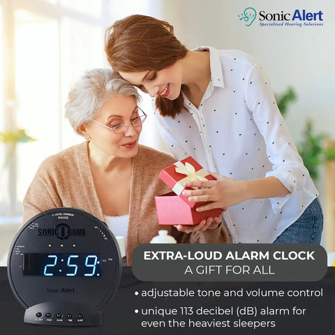 Heavy Duty Alarm Clock For Stubborn Sleepers With Rock Solid Bed Shaker Glaring Red Strobe Lights Serious Sonic Punch Adjustable Dual Morning Wake Calls With Backup Battery Reserve being gifted by a young woman to an older woman.