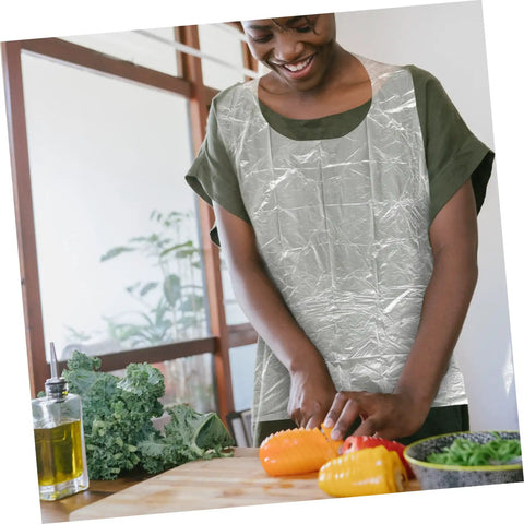 Get Ready To Tackle The Mess With This Slick Rock Solid Pack Of Twenty Five Chemical Resistant Waterproof Sleeveless Aprons In Transparent Plastic Perfect For Kitchen Grilling And Dirty Chores Giving You Zero Stress And Total Victory Today, a woman using a clear apron chopping vegetables.