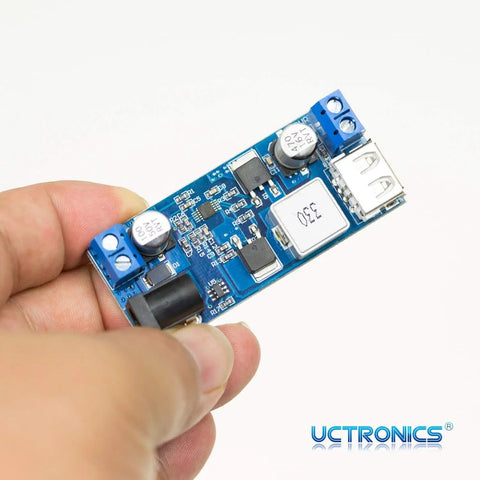 Hand holding Plug And Play Dual USB 5V Buck Converter from 9V to 36V input with stable 5V output up to 6A, showing USB port and components