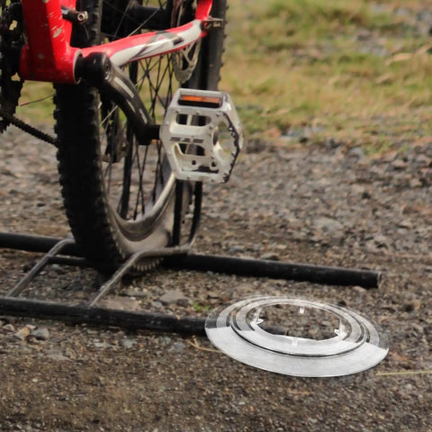 Chain Guard And Spoke Protector For Mountain And Road Bikes next to a bike on gravel path.
