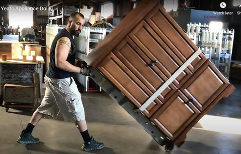 Person using a Sturdy 71 Inch Aluminum Appliance Dolly With Thick Felt Pads And Secure Ratchet Straps to lift a heavy cabinet.