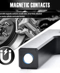 Front view of VKQTS brake booster adjustment tool; black handle with blue-ring button, rotor and caliper in background.