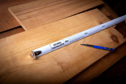 25 Foot Self Locking Tape Measure Auto Retract Hi Vis Blade with Decimal Equivalents on wood backdrop and pen.
