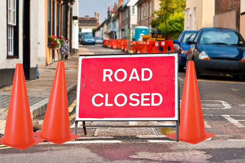 12 Inch Traffic Training Sports Cones 10 Pack Or 24 Pack Orange Safety Markers next to 'Road Closed' sign on street