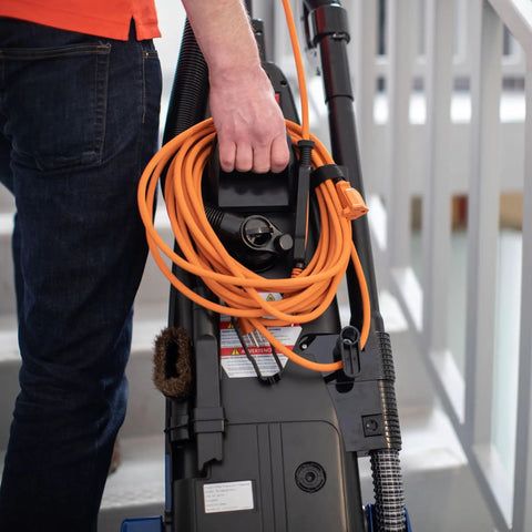 Person holding Powr-Flite Borelli Dual Pro Upright Vacuum With HEPA Filtration for heavy duty use with orange cord.