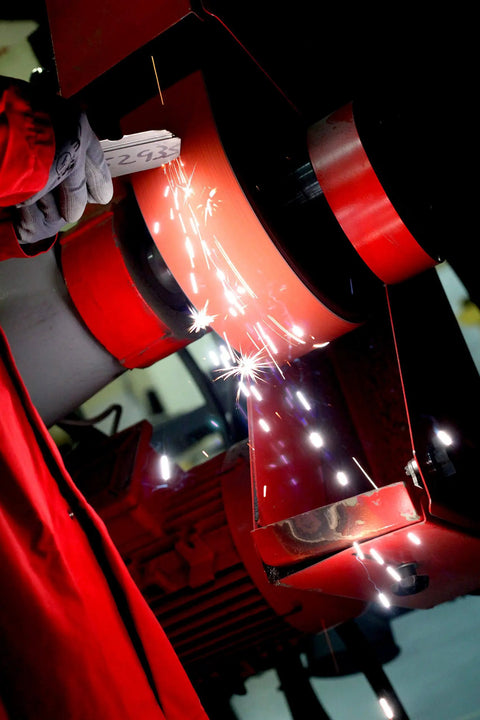 Person using Cubitron Ceramic Cloth Sanding Belt 4.5 x 60 in P80 JE-Weight Orange on machine, sparks visible
