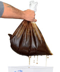 Hand holding Cold Brew Wide PLA Filter 40 Pack Natural White For Commercial Brewers, extra wide overtop fit, dripping coffee.