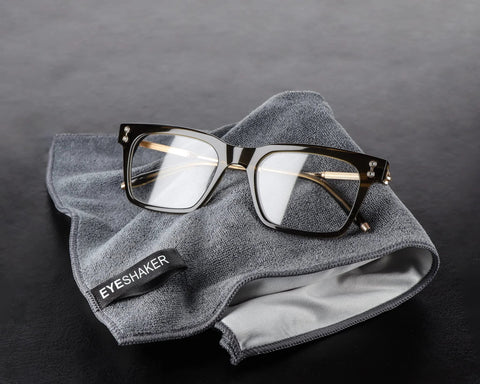 Glasses cleaning cloth (30 × 20 cm) microfiber gray with EYESHAKER logo, shown with eyeglasses.