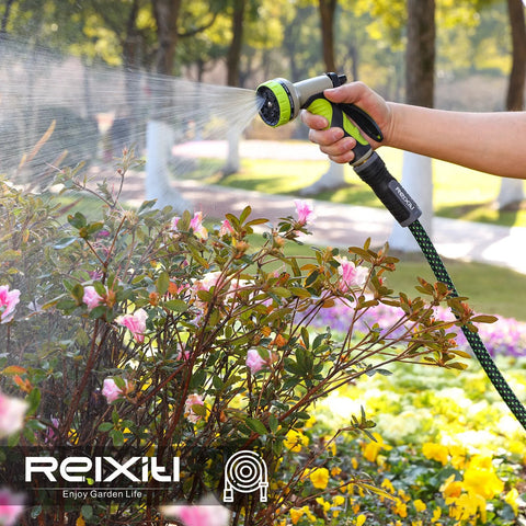 Relxitl garden hose with green and black 10-function spray nozzle, watering pink flowering shrubs.