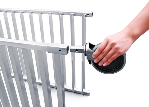 Hand attaching a locking brake wheel to the No Sweat Commercial Aluminum Sheet Pan Rack for easy mobility.