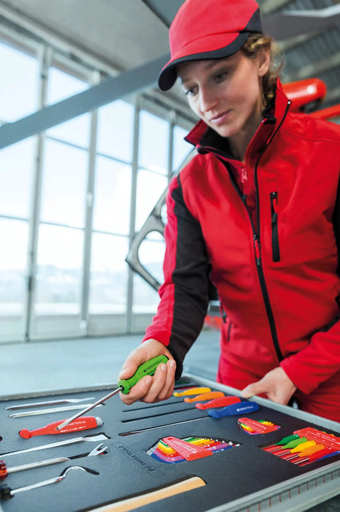 Person in red outfit examines ratcheting screwdriver with one hand switch left right lock magnetic bit holder in toolkit