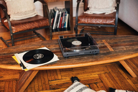 Audio-Technica at-LPGO-BT belt-drive wireless turntable, gun-metal/black, on a wooden coffee table with vinyl records (2).