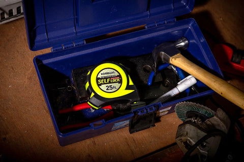 25 Foot Self Locking Tape Measure Auto Retract Hi Vis Blade in blue toolbox with tools, rugged design for pros.