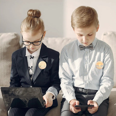 Children sitting with digital devices wearing buttons from the Bulk 400 Piece Button Making Kit No Brainer With Fifty Eight Millimeter Button Parts
