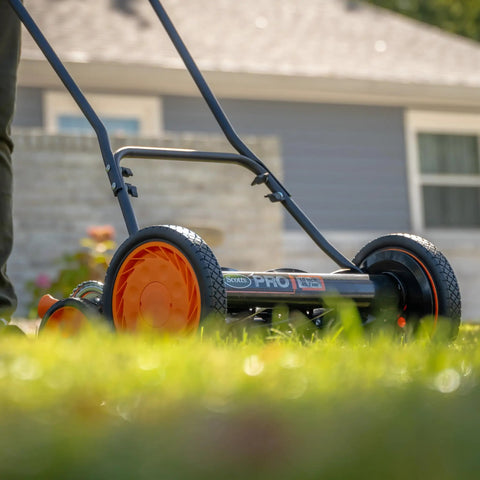 Old School 18 Inch Manual Reel Mower With 7 Blade Ball Bearing Reel Push Style Adjustable Cutting Height From 1 To 3 Inches 10 Inch Dual Tracking Wheels Heat Treated Alloy Steel Blades Green shown in use on lawn