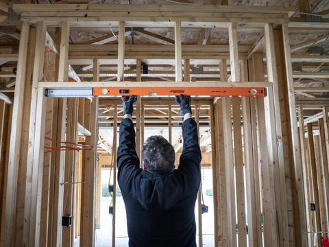 Person using Hefty 48 To 80 Inch Telescoping Box Beam Level With Lock Tight Extension for accurate leveling on a construction site.