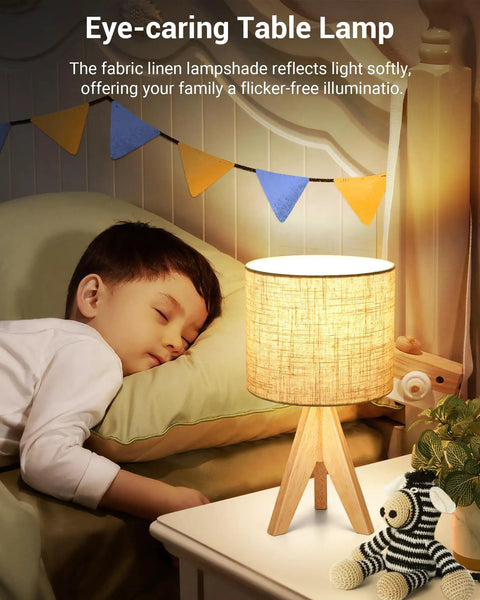 Boho Wood Tripod Table Lamp With Linen Fabric Shade For Nightstand Or Bedside Use Cozy Warm Glow For Living Room Bedroom Nursery Or Kids Room Fourteen Point Two Inch Tall With Simple On Off Switch next to sleeping child