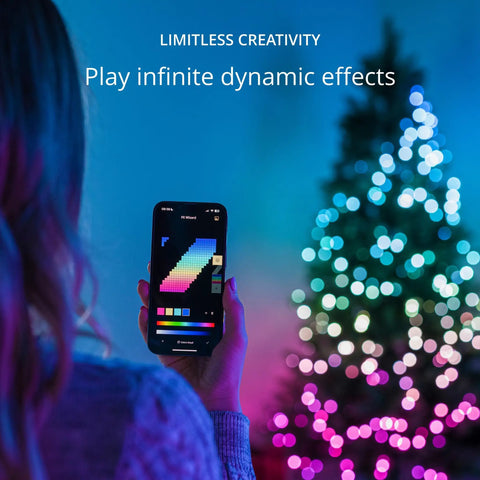 Person using app to control App Controlled 105 Foot Smart String LED Lights With 400 RGB White LEDs, WiFi And Bluetooth Connectivity, Music Sync, Indoor And Outdoor IP44 Rated, Works With Google Assistant And Amazon Alexa, in front of a decorated tree.
