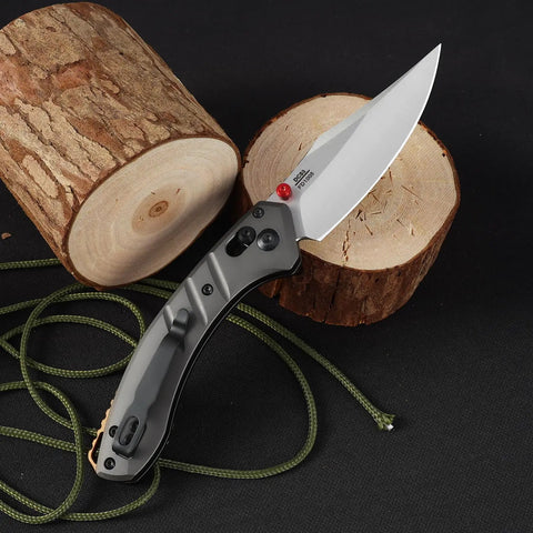 Premium Folding Pocket Knife With Top Shelf Dc53 Steel Blade And Rock Solid Aluminum Handle Loaded With A Slim Deep Carry Clip For Camping Hiking Backyard Grind And Daily Carry In Matte Grey on wood logs.