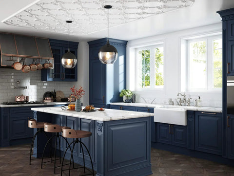 Edwardian Widespread Bridge Kitchen Faucet With Side Spray In Pure Unlacquered Brass above a stylish blue kitchen island.