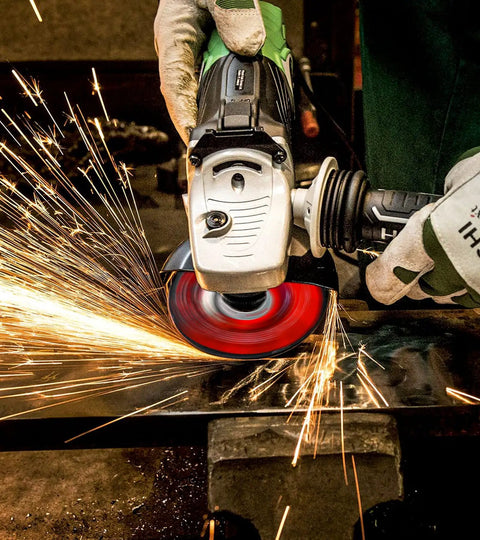 Angle grinder with Twenty Five Pack Of Four And A Half Inch Grinding Wheels For Angle Grinders Built Tough For Fast Metal Grinding Rust Removal Deburring And Cleaning With Seven Eighths Inch Arbor in use, emitting sparks while grinding metal.