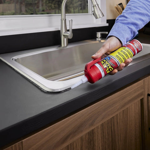 Flex Caulk 9 oz white hybrid polymer sealant being applied along a kitchen sink edge.