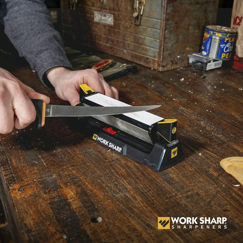 Three Sided Benchstone Knife Sharpener with diamond and ceramic abrasives in use, adjustable guides on a workshop table.