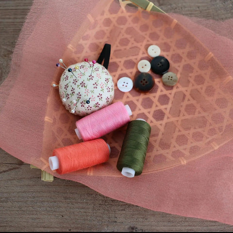 Top Shelf 72 Piece Sewing Thread Kit With 36 Vibrant Polyester Shades And Matching Bobbins and spools on fabric with pins.