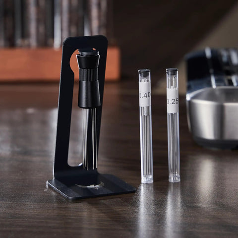 Hella Smooth Breville Espresso Accessories Kit With Bottomless Portafilter Plus Spring Loaded Tamper Featuring Rosewood Knock Box And Wdt Needle Distribution Station with WDT needle holder and measuring needles on a wooden table.